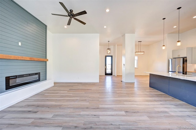 unfurnished living room with light wood-style flooring, a fireplace, a ceiling fan, and recessed lighting