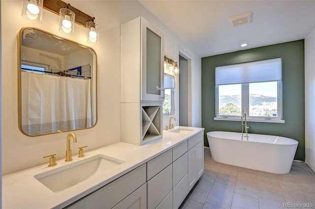 bathroom featuring double vanity, tile patterned flooring, a freestanding bath, and a sink