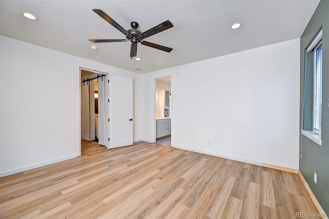 interior space featuring ceiling fan, a barn door, recessed lighting, baseboards, and light wood finished floors