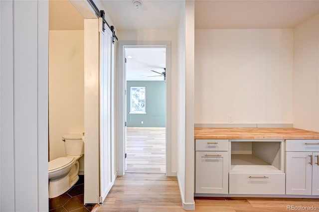 bathroom featuring baseboards, ceiling fan, toilet, and wood finished floors