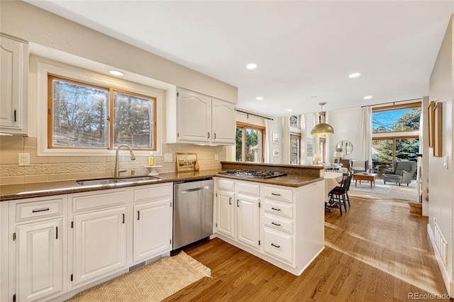 kitchen featuring white cabinets, sink, light hardwood / wood-style flooring, kitchen peninsula, and stainless steel appliances