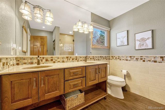 bathroom featuring wood-type flooring, an enclosed shower, toilet, vanity, and tile walls