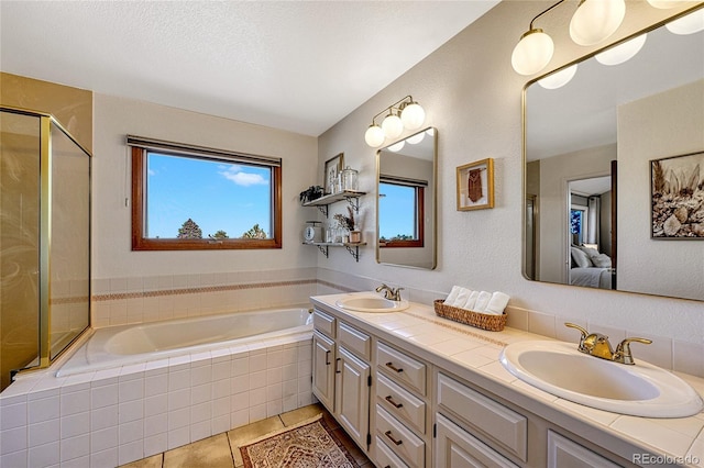 bathroom with tile patterned floors, vanity, and a relaxing tiled tub