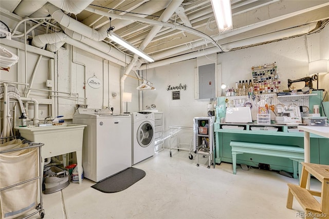 clothes washing area with washing machine and clothes dryer, electric panel, and a workshop area