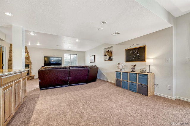 carpeted living room featuring a stone fireplace and a textured ceiling