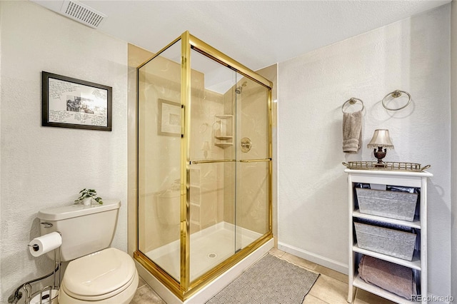 bathroom with tile patterned floors, toilet, and a shower with door