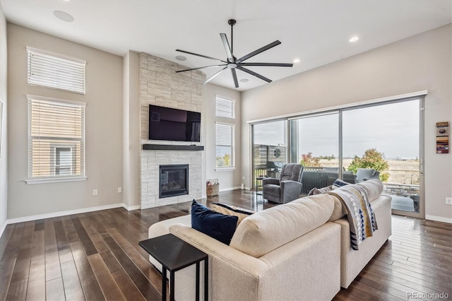 living room with dark wood-type flooring, a fireplace, and ceiling fan