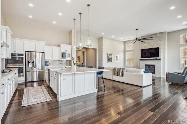 kitchen featuring appliances with stainless steel finishes, white cabinetry, a kitchen island with sink, and dark wood-type flooring