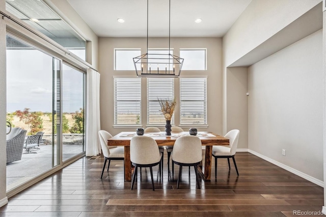 dining space with a wealth of natural light, dark wood-type flooring, and an inviting chandelier