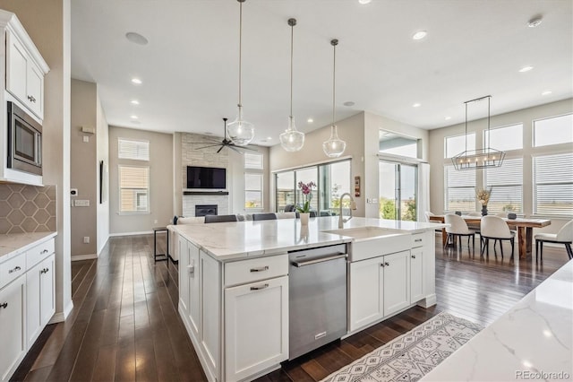 kitchen featuring tasteful backsplash, appliances with stainless steel finishes, white cabinetry, a fireplace, and decorative light fixtures