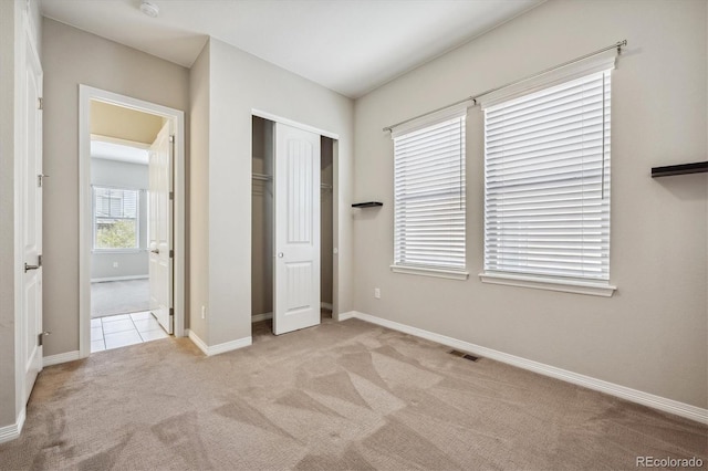 unfurnished bedroom featuring a closet and light colored carpet