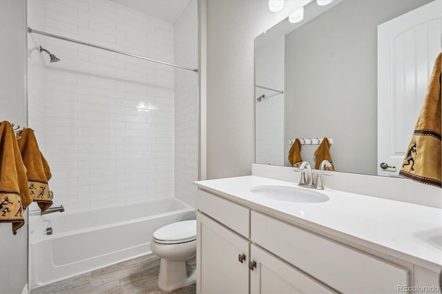 full bathroom with tiled shower / bath, vanity, hardwood / wood-style flooring, and toilet