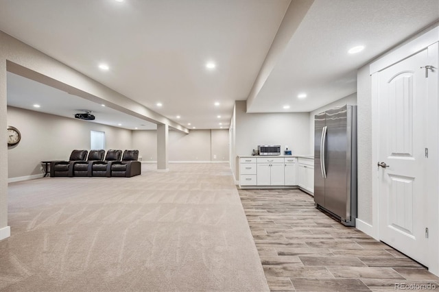 kitchen with appliances with stainless steel finishes, light carpet, and white cabinets