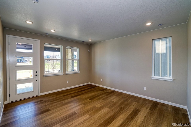 spare room featuring baseboards, a textured ceiling, and dark wood-type flooring