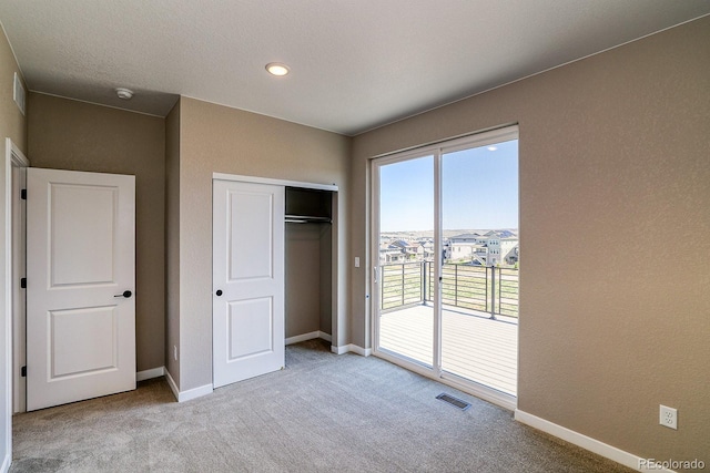 unfurnished bedroom featuring baseboards, carpet, visible vents, access to outside, and a closet