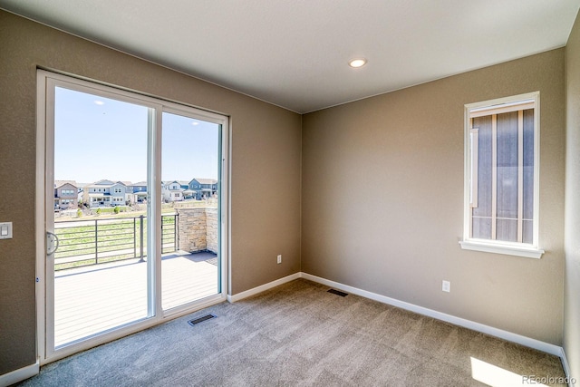 carpeted spare room featuring baseboards, visible vents, and plenty of natural light