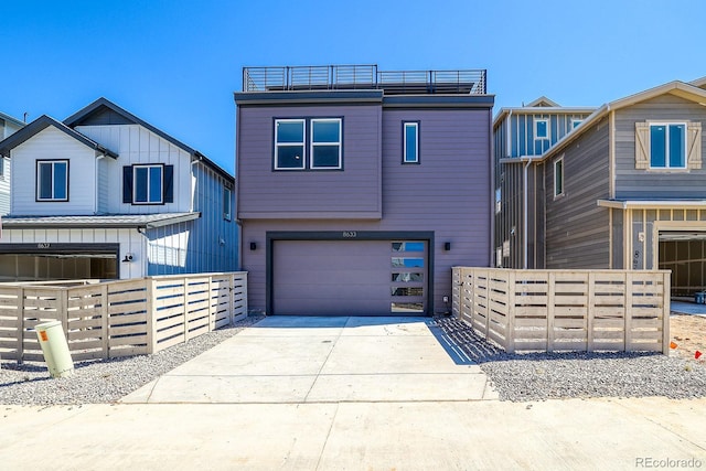 view of front of house featuring concrete driveway, fence, and a garage