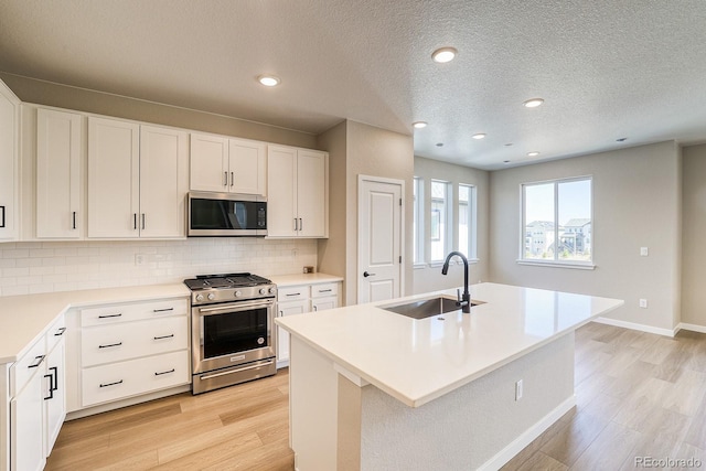 kitchen with decorative backsplash, stainless steel appliances, light wood-style flooring, and a sink