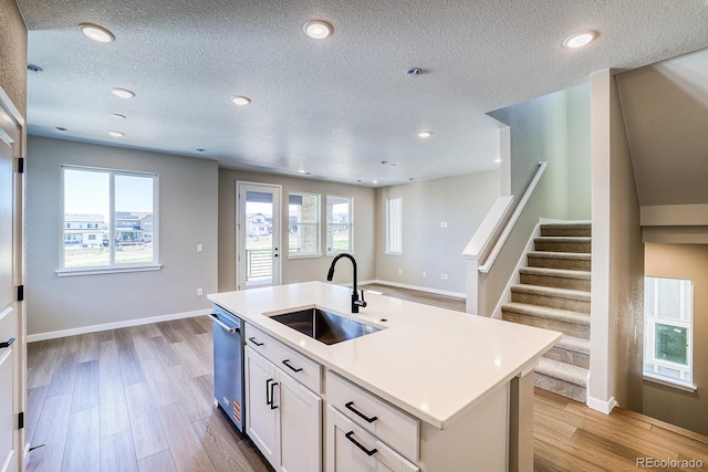 kitchen featuring white cabinets, light countertops, a sink, and a textured ceiling