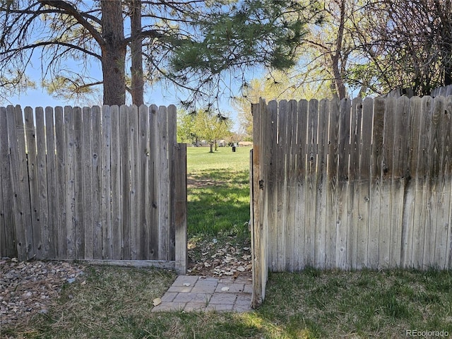 view of gate with fence and a lawn
