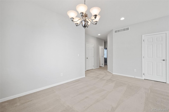 spare room featuring a notable chandelier and light carpet