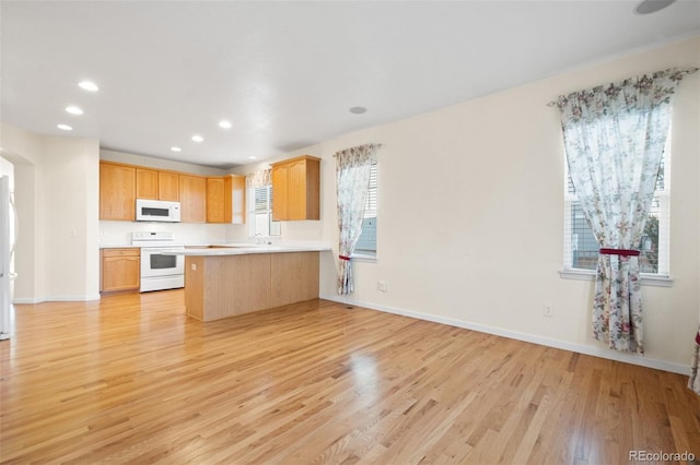 kitchen with kitchen peninsula, white appliances, and light hardwood / wood-style flooring