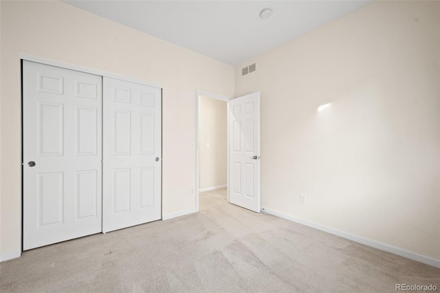 unfurnished bedroom with light carpet and a closet