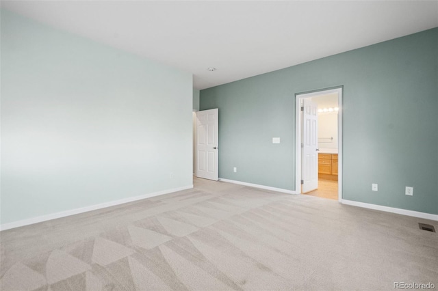 unfurnished bedroom featuring light carpet and ensuite bathroom