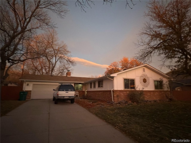 view of front of house featuring stucco siding, concrete driveway, a garage, brick siding, and a chimney