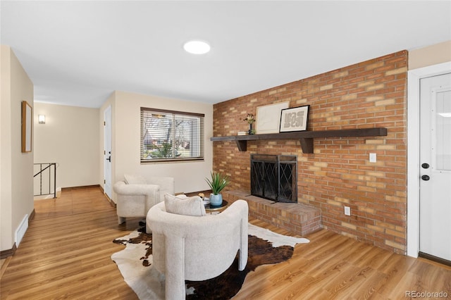 living area with visible vents, a brick fireplace, wood finished floors, and brick wall