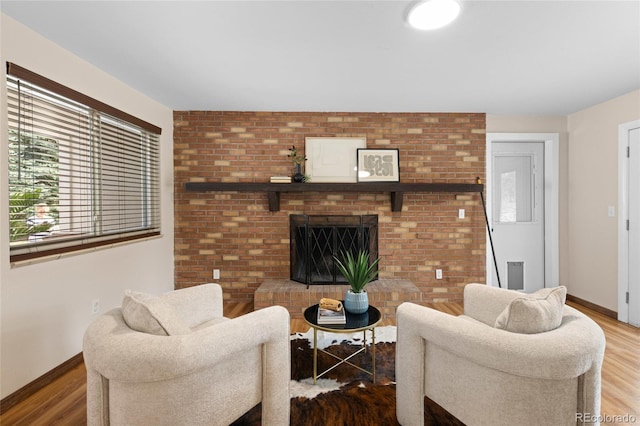 living area featuring a fireplace, baseboards, and wood finished floors