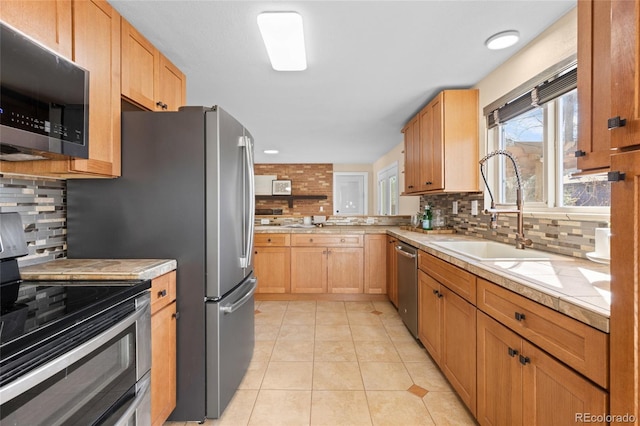 kitchen featuring tasteful backsplash, light brown cabinetry, light tile patterned floors, appliances with stainless steel finishes, and a sink