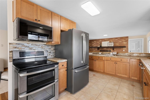 kitchen with stainless steel appliances, tasteful backsplash, light tile patterned flooring, and light countertops