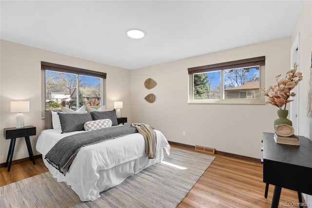 bedroom with visible vents, baseboards, and light wood finished floors