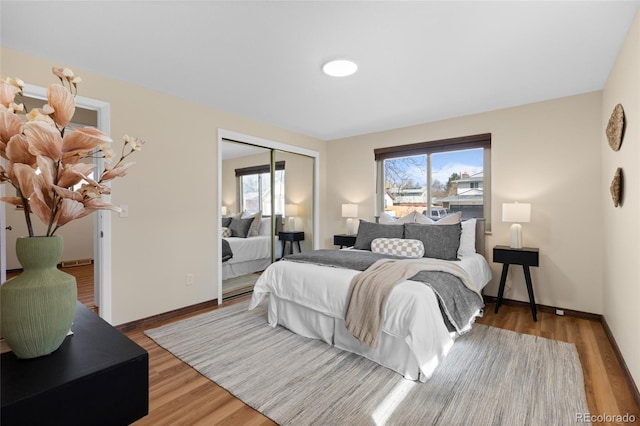 bedroom with multiple windows, wood finished floors, a closet, and baseboards