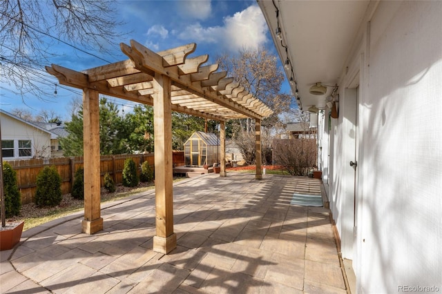 view of patio with an outbuilding, a greenhouse, a fenced backyard, and a pergola