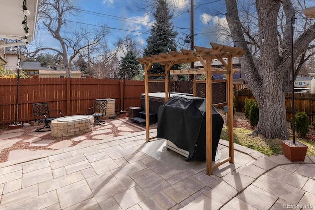 view of patio featuring grilling area, an outdoor fire pit, a fenced backyard, a jacuzzi, and a pergola