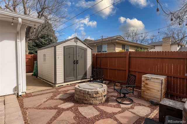 view of patio with an outdoor structure, a fire pit, a fenced backyard, and a shed