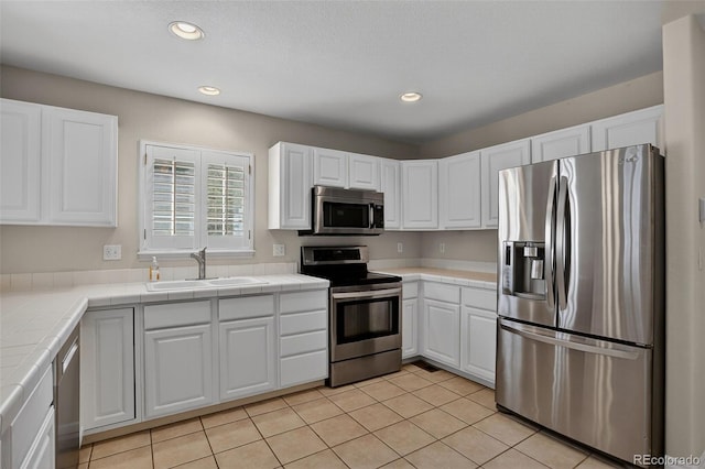 7400 W Grant Ranch Blvd Unit 9, Littleton, CO 80123 - kitchen featuring stainless steel appliances, tile countertops, white cabinets, recessed lighting, and light tile patterned flooring