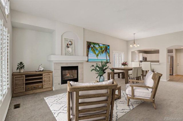 7400 W Grant Ranch Blvd Unit 9, Littleton, CO 80123 - living room featuring light carpet, a tiled fireplace, and arched walkways