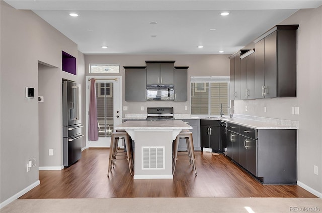 kitchen with gray cabinets, black appliances, a breakfast bar area, and a kitchen island