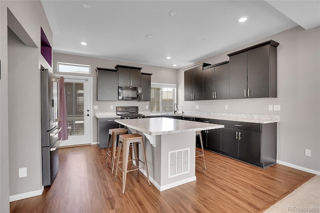 kitchen featuring high end refrigerator, a kitchen island, a breakfast bar, sink, and light hardwood / wood-style flooring