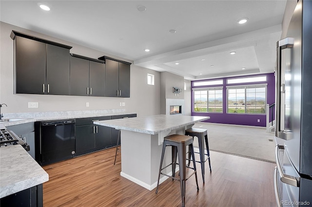 kitchen featuring high quality fridge, black dishwasher, a breakfast bar area, and a kitchen island