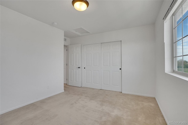 unfurnished bedroom with light colored carpet and a closet