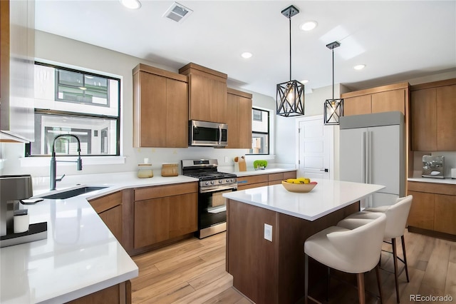 2076 S Holly St Unit 1, Denver, CO 80222 - kitchen with stainless steel appliances, light wood finished floors, a breakfast bar, a center island, and hanging light fixtures