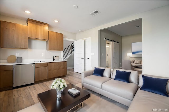 2076 S Holly St Unit 1, Denver, CO 80222 - living area featuring a barn door, light wood-style flooring, and recessed lighting