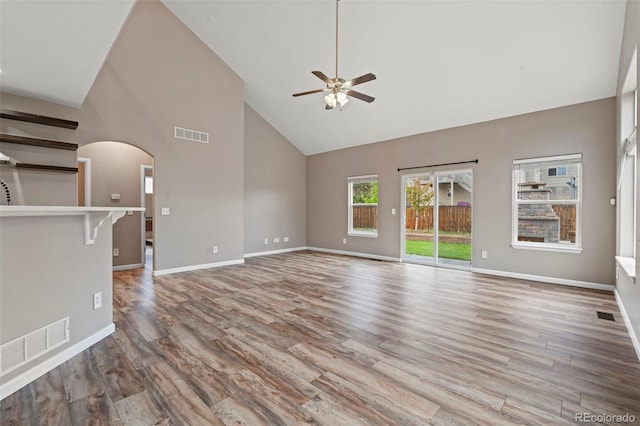 12532 Mount Belford Way, Peyton, CO 80831 - unfurnished living room featuring a ceiling fan, high vaulted ceiling, arched walkways, wood finished floors, and baseboards