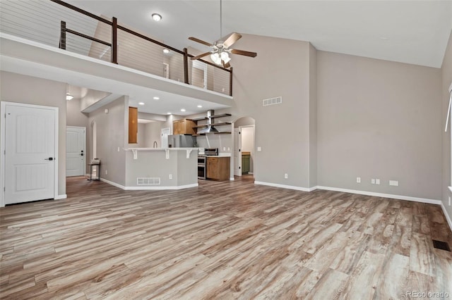 12532 Mount Belford Way, Peyton, CO 80831 - unfurnished living room with a towering ceiling, ceiling fan, light wood-style flooring, and baseboards