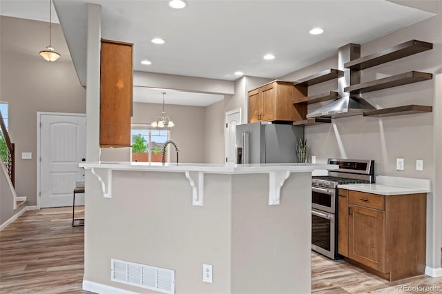 12532 Mount Belford Way, Peyton, CO 80831 - kitchen with stainless steel appliances, open shelves, a breakfast bar, brown cabinetry, and light wood-style flooring