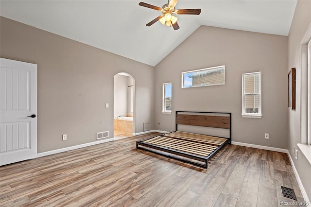 12532 Mount Belford Way, Peyton, CO 80831 - bedroom featuring arched walkways, wood finished floors, high vaulted ceiling, ensuite bathroom, and baseboards
